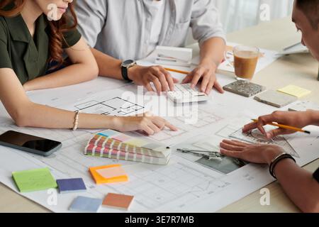 Équipe d'architectes asiatiques et de designers d'intérieur travaillant sur le plan de la maison assis au bureau dans le bureau Banque D'Images