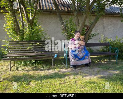 Femme en surpoids assise sur un banc de jardin et embrassant son chien pendant une journée ensoleillée en République tchèque Banque D'Images