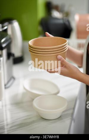 Mains de femme asiatique tenant pile de bols tout en se tenant debout dans la cuisine à la maison Banque D'Images