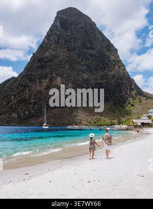 Un couple romantique se promène le long de la plage de sable de Sainte-Lucie, en admirant la vue imprenable sur les emblématiques Pitons. Banque D'Images