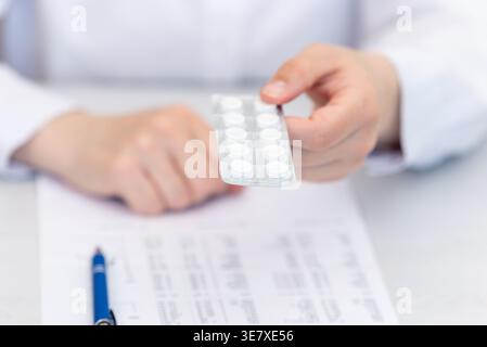 Médecin tenant le blister paquet de comprimés sur des documents médicaux, prescription et concept de planification de traitement Banque D'Images