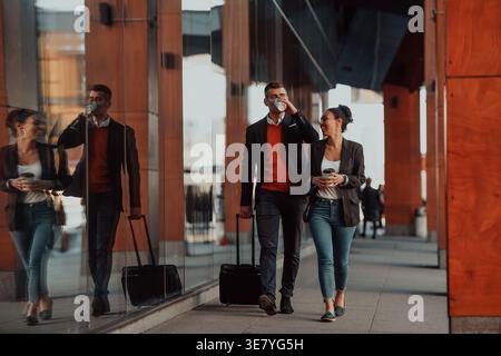 Femme d'affaires hispanique souriante et homme d'affaires caucasien avec des bagages ayant une pause café du travail marchant dans la rue de la ville pendant la journée Banque D'Images