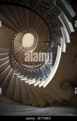 Vue sur un grand escalier en pierre sinueux avec des balustrades complexes en fer forgé et un sens de l'architecture intemporelle Banque D'Images