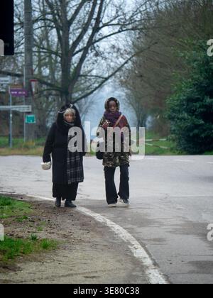 Femme noire et femme âgée caucasienne portant des vêtements chauds parlant tout en marchant ensemble sur la route pendant l'hiver Banque D'Images