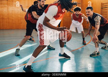 Homme du moyen-Orient avec des dreadlocks jouant au basket-ball avec des coéquipiers sur le terrain Banque D'Images