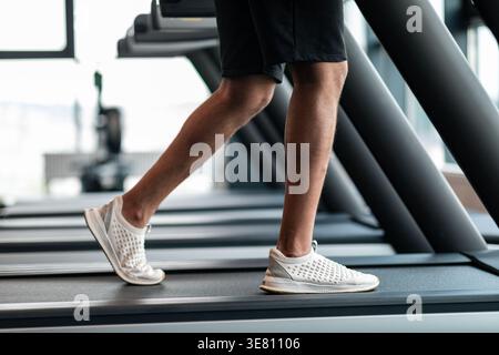 Image recadrée de Black Man jogging sur tapis roulant dans le gymnase Banque D'Images