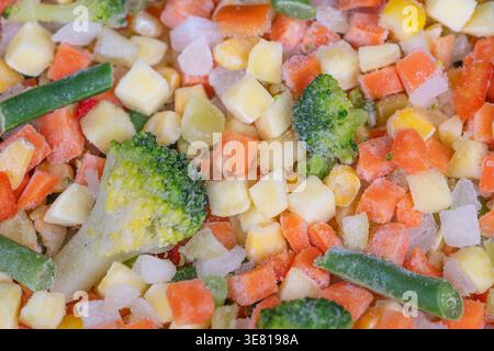 Mélange de légumes surgelés en gros plan avec des légumes en dés colorés et une texture givrée, mis en place pour les parents occupés à préparer des repas de famille et des plats d'accompagnement sains h. Banque D'Images