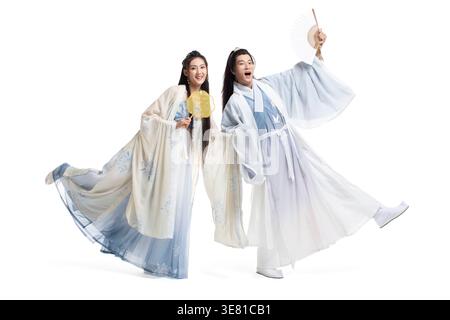 Joyeux couple chinois en costume ancien tenant des fans tout en se tenant debout sur fond blanc dans le studio Banque D'Images