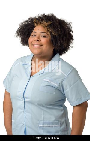 Femme hispanique de grande taille souriante avec afro bouclé portant un uniforme bleu debout sur fond blanc en studio Banque D'Images