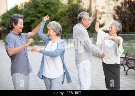 Joyeux couples chinois âgés dansant dans le parc Banque D'Images