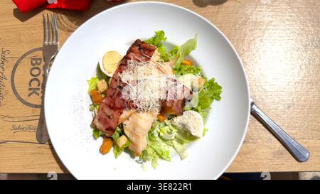 Vue aérienne d'une salade césar de poulet avec bacon grillé et fromage parmesan sur une assiette blanche à une table de marque Super Bock Banque D'Images