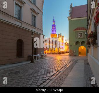 Vue tôt le matin de l'hôtel de ville de Poznan depuis une rue calme sur la place du vieux marché, Poznan, Pologne, avec des façades illuminées à l'heure bleue avant le soleil Banque D'Images