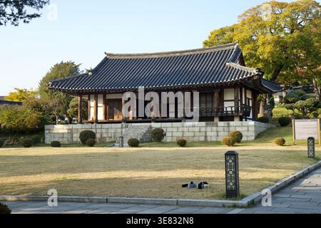 Le hall principal en bois d'Ulsan Dongheon et Naea se dresse au-dessus d'une pelouse taillée, avec un toit en tuiles, une plate-forme en pierre et des arbustes à travers le patrimoine Banque D'Images