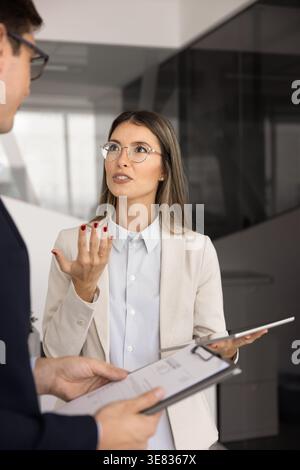 Professionnelle confiante engagée dans des discussions professionnelles sérieuses avec un collègue Banque D'Images