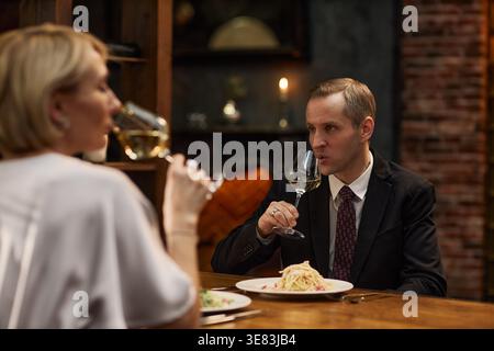 Couple d'âge moyen buvant du vin pendant le dîner-réunion Banque D'Images