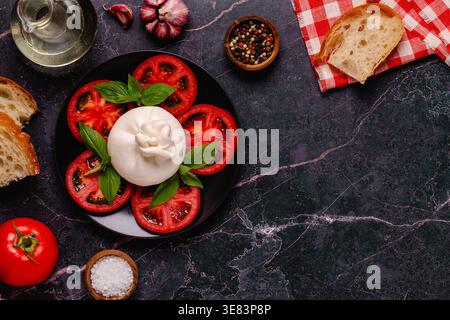 Salade Caprese avec tomates, burrata et basilic. Fond sombre. Vue de dessus. Banque D'Images
