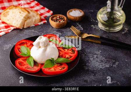 Salade Caprese avec tomates, burrata et basilic. Fond sombre. Banque D'Images
