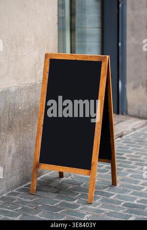 Tableau noir blanc en bois panneau a-cadre debout sur un trottoir pavé Banque D'Images