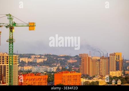 Dnipro, Ukraine ville skyline avec grue de construction imposante et bâtiments résidentiels modernes contre un ciel brumeux, mettant en valeur le développement urbain et di Banque D'Images