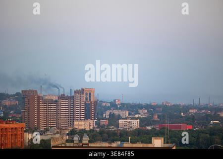 Dnipro, Ukraine, une vue panoramique de la ville le 19 mai 2023, des bâtiments résidentiels modernes, des cheminées industrielles émettant du panache, et un terrain urbain diversifié Banque D'Images