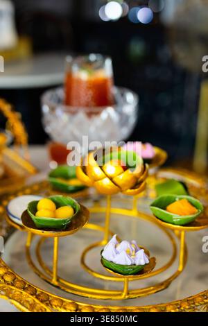 Service de thé de luxe sur une table en marbre avec support doré orné contenant des desserts et des fruits variés, boissons glacées et café bokeh bac Banque D'Images