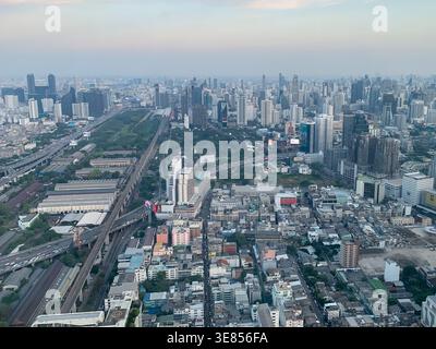 Une vue aérienne panoramique montre des autoroutes traversant une ville urbaine dense. Des gratte-ciel s'élèvent à l'horizon dans une métropole tentaculaire. Banque D'Images