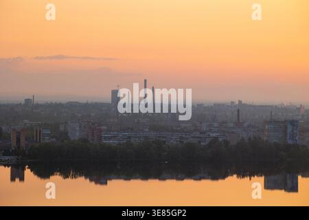Dnipro, Ukraine – 19 mai 2023 : une vue aérienne du paysage urbain de Dnipro à l'aube, des cheminées industrielles, des bâtiments résidentiels et des lignes d'arbres reflétant Banque D'Images