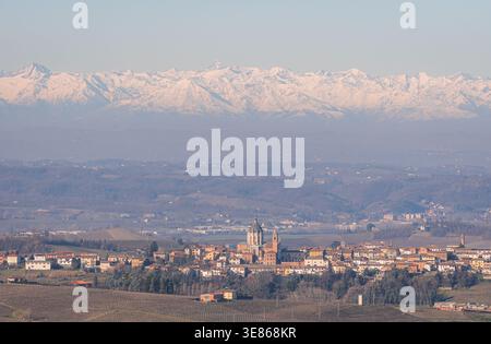 Vue matinale du village de Piamonte en Italie, entouré de collines ondulantes et de montagnes enneigées lointaines. Le paysage paisible capture l'essence Banque D'Images