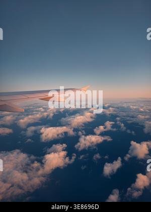 Vue de l'aile d'avion au-dessus des nuages d'hiver moelleux au-dessus de la mer, avec des teintes de coucher de soleil dans le ciel. Capturé à partir d'un vol approchant de Tenerife, mettant en évidence la victoire Banque D'Images