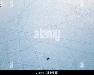 Vue aérienne minimaliste d'un large champ enneigé gravé de pistes sinueuses de ski et de skate, créant des lignes et des textures abstraites dans un finnois calme Banque D'Images