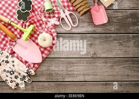 Des outils de jardinage assortis, notamment des truelles, des gants et de la ficelle, soigneusement disposés sur une table en bois, évoquent un cadre printanier frais idéal pour plantin Banque D'Images