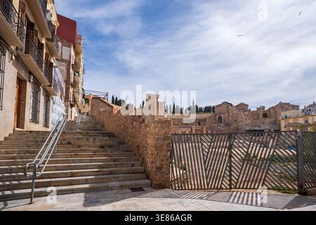 Vue urbaine évocatrice à Carthagène, Espagne, avec un escalier moderne flanqué de bâtiments historiques menant aux ruines du théâtre romain antique. Le c Banque D'Images