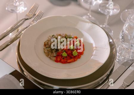 Hors-d'œuvre gastronomique avec tartare de poisson servi sur une assiette élégante, table de restaurant gastronomique Banque D'Images