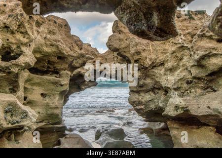 Une grande formation rocheuse avec un trou au milieu. Le trou est entouré de rochers et l'eau est calme Banque D'Images