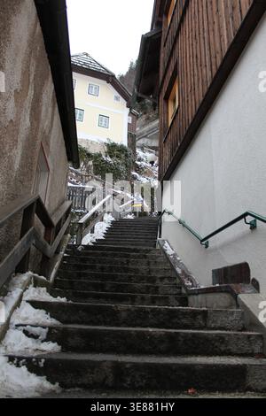 Escaliers en pierre escarpés bordés de vent de neige entre des maisons traditionnelles en bois et en plâtre dans le village historique de Hallstatt, en Autriche. Banque D'Images