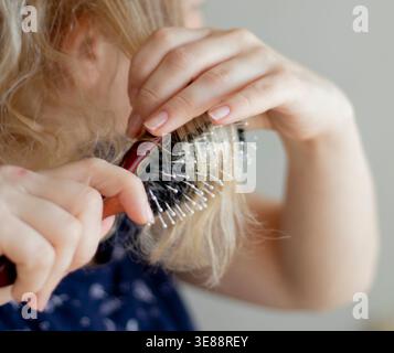 mise au point sélective. blond peignant les cheveux mouillés et emmêlés. Banque D'Images