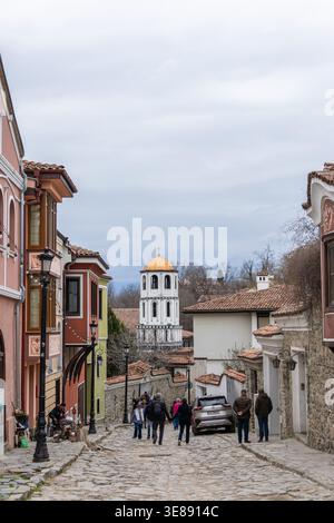 Les touristes explorent les anciennes rues pavées de Plovdiv, Bulgarie. Avec des maisons historiques colorées et une belle tour d'église orthodoxe sous Banque D'Images