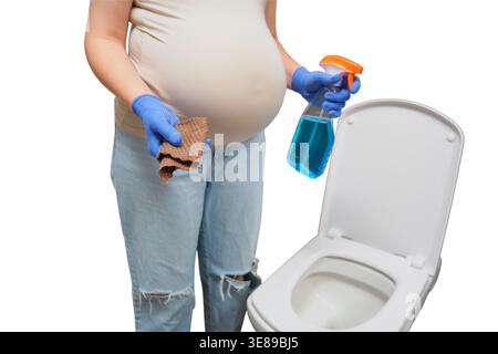 Femme enceinte nettoyant les toilettes avec vaporisateur et chiffon. Femme enceinte faisant les tâches ménagères. Maintien de l'hygiène à la maison pendant la grossesse. Da Banque D'Images