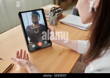 Jeune femme adulte assistant à un appel vidéo sur tablette, confrontée à une mauvaise connexion lors d'une communication à distance avec l'homme. Utile pour le travail à distance, l'assistance en ligne, les concepts d'interruption de téléconférence Banque D'Images