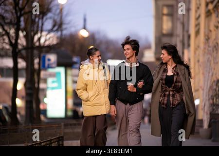Jeune homme et deux femmes marchant ensemble dans la rue de la ville. Banque D'Images
