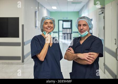 Portrait d'une équipe médicale caucasienne d'âge moyen debout dans le couloir de l'hôpital, souriant et posant dans les gommages. Soutenir le personnel de santé, la promotion clinique, le marketing des services médicaux Banque D'Images