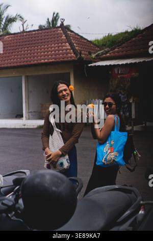 Deux jeunes amis asiatiques souriants avec du souci posant dans la rue à Bali Banque D'Images