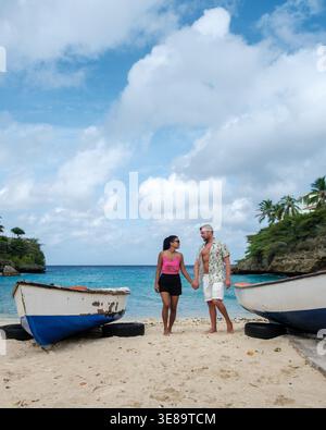 Sur la pittoresque plage Playa Lagun à Curaçao, un couple partage un moment romantique main dans la main. Banque D'Images