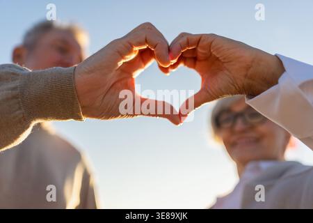 Amour coeur en forme de paix. Couple âgé senior qui fait le cœur avec ses mains. Femme adulte mature et ancien mari montrant un signe de coeur. Bonne famille de pensionnés. Je vous aime bonne Saint Valentin Banque D'Images