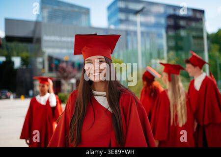 Jeune femme souriante diplômée en casquette et robe lors de la cérémonie de remise des diplômes universitaires. Banque D'Images
