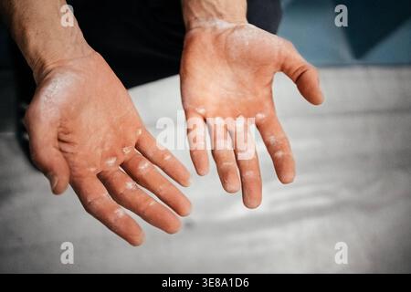 Mains grimpantes mâles recouvertes de craie après Hard route : gros plan sur les doigts usés et la peau scotchée. Photo de haute qualité Banque D'Images