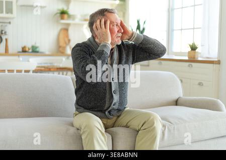 Maux de tête. Malheureux homme âgé d'âge moyen souffrant de maux de tête malade frottant les tempes à la maison. Vieux grand-père aîné mature touchant les temples éprouvant du stress. Homme sentant mal à la tête Banque D'Images