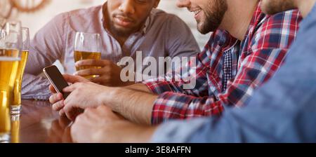 Man Nouvelle application sur Smartphone, se reposant dans un bar avec des amis Banque D'Images