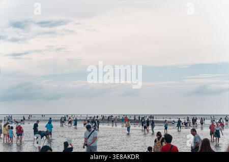 Taichung, Taiwan - 26 mai 2024 : la foule marche et joue sur les marées peu profondes de Gaomei Wetland sous un ciel lumineux partiellement nuageux un jour d'été. Banque D'Images