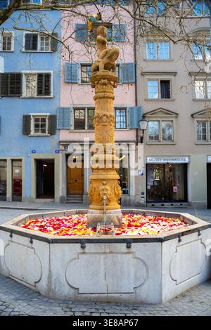 Zurich, Suisse - 2 avril 2026 : la fontaine Froschauerbrunnen de Zurich, place Zahringerplatz, remplie de pétales de rose à Pâques Banque D'Images